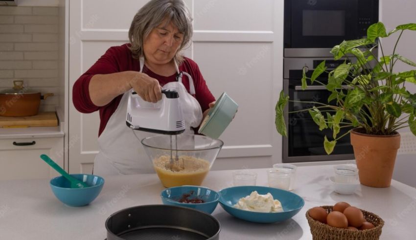An older woman mixing ingredients in a kitchen.