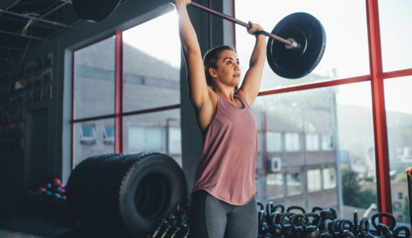 A woman lifting a barbell in a gym.