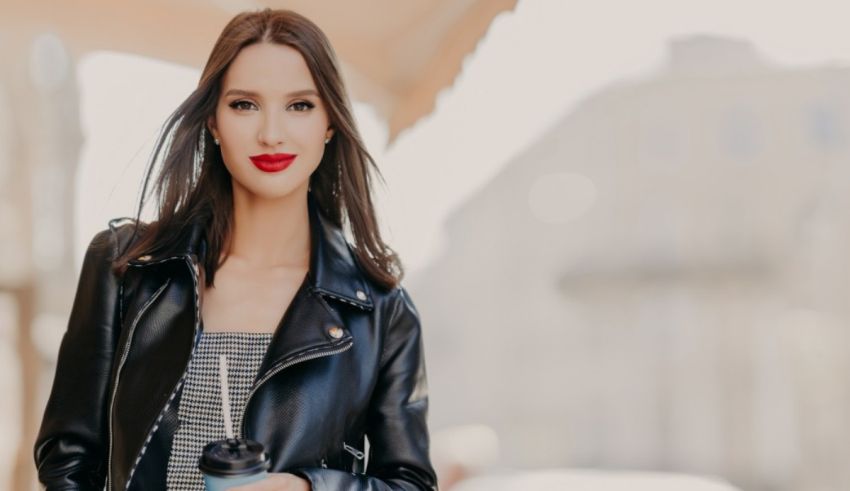 A woman in a black leather jacket is holding a cup of coffee.