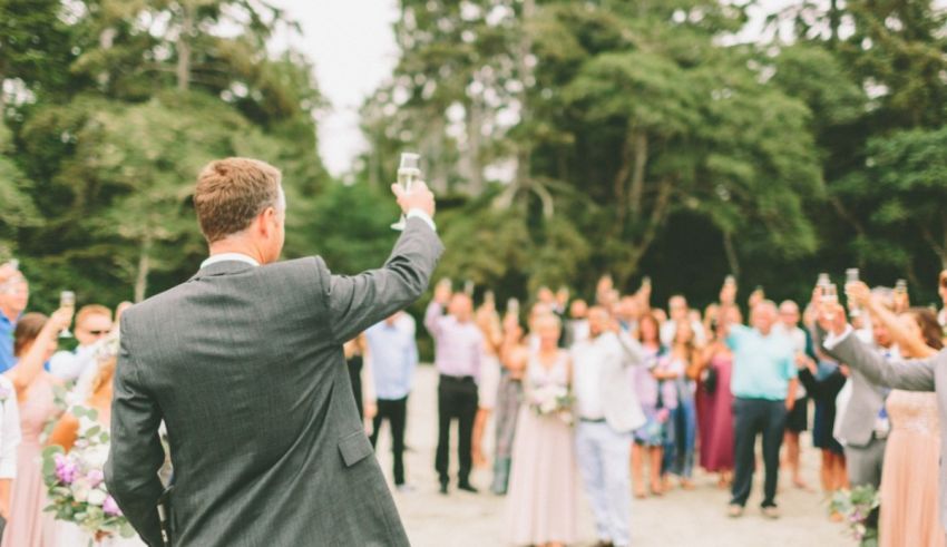 A man in a suit raises his glass to the crowd.