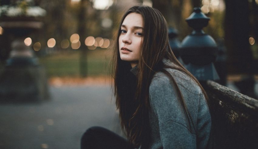 A young woman sitting on a bench in a park.