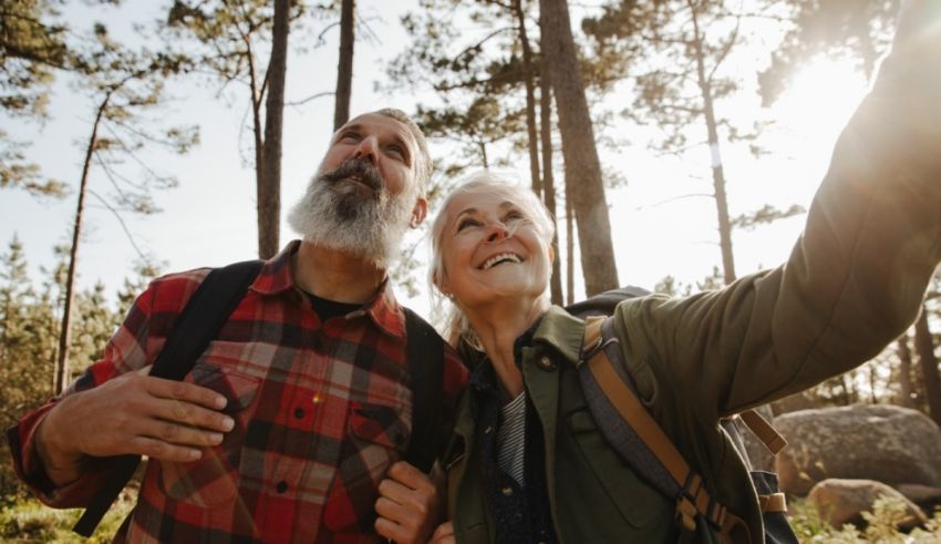 An older couple taking a selfie in the woods.