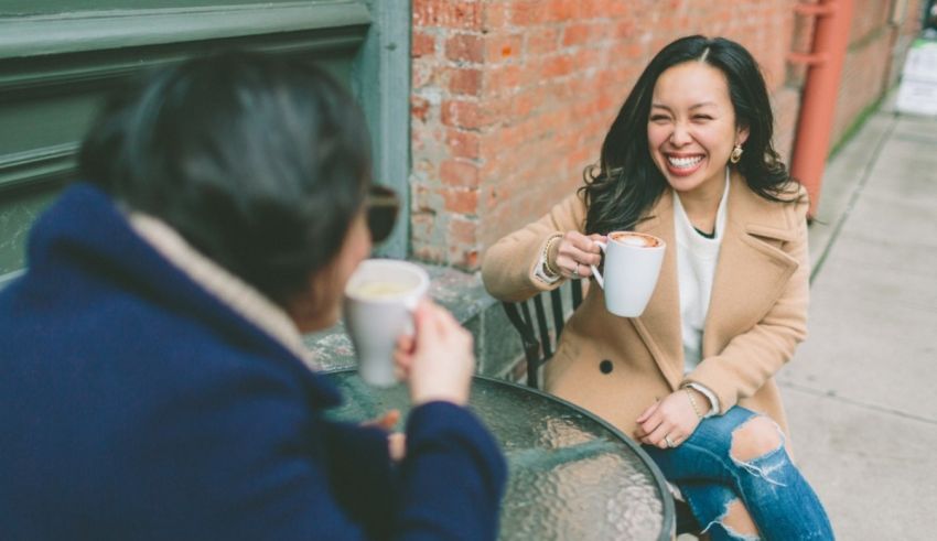 Two women sitting at an outdoor table drinking coffee.
