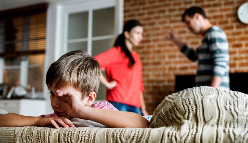A young boy laying on a couch with a woman and man in the background.