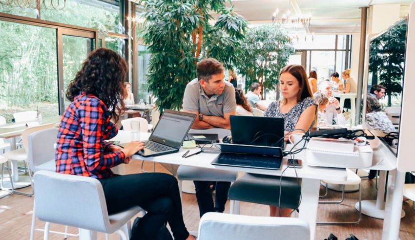 A group of people sitting around a table with laptops.