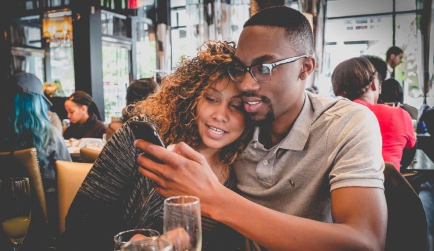 A man and woman looking at a cell phone in a restaurant.