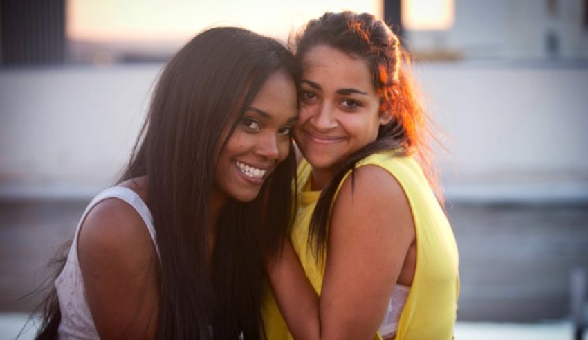 Two black women posing for a photo in front of a building.