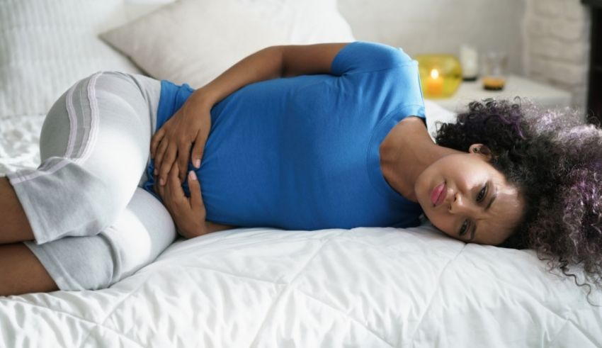 A woman laying on a bed with a stomachache.
