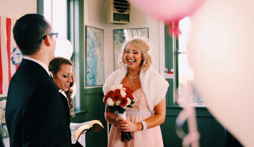 A bride and groom smiling at each other in a room with balloons.