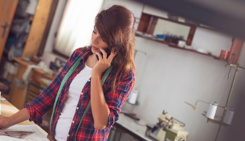 A woman talking on the phone while working in a sewing room.