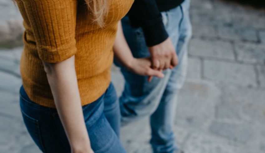 A man and woman holding hands walking down a street.