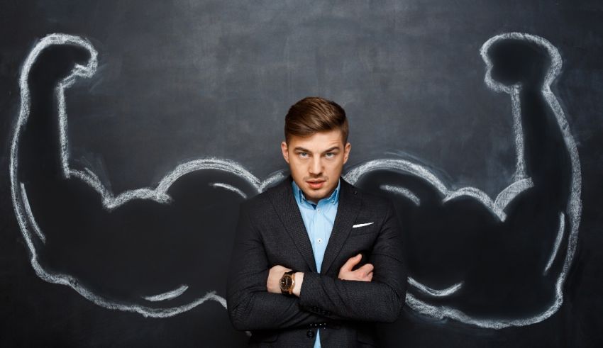 A businessman standing in front of a chalkboard with biceps drawn on it.
