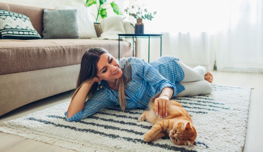 A young woman laying on the floor with a cat.