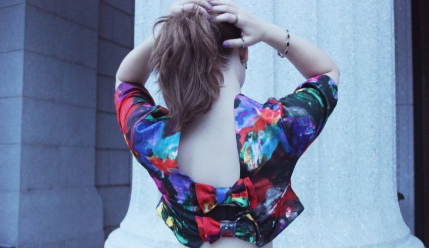 A woman wearing a colorful top and backwards hat.