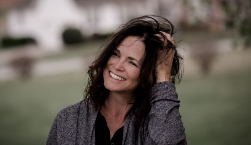 A woman smiling with her hand in her hair.