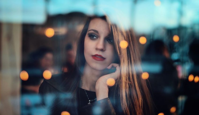 A woman looking at herself through a glass window.