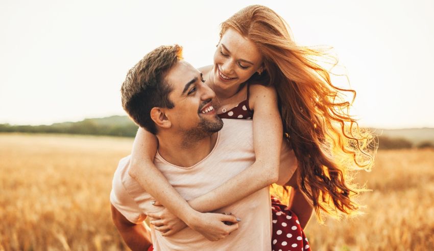 A man and woman hugging in a field at sunset.