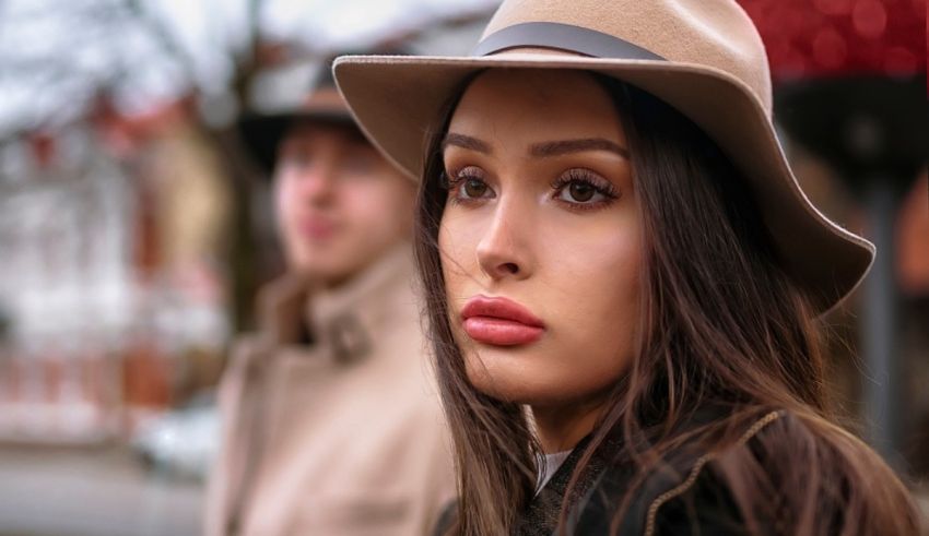 A woman in a hat is standing next to a man.