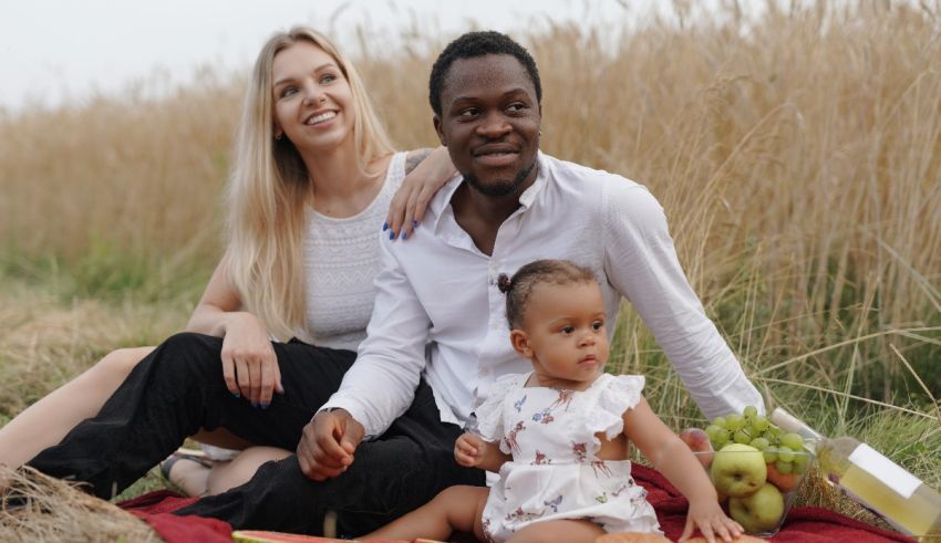 A family sitting on a blanket in a field with a baby.