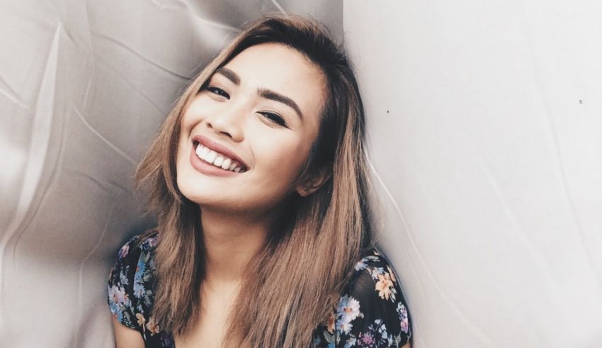 A woman smiling while leaning against a wall.