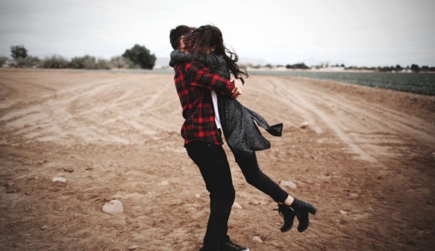 A man and woman hugging in a field.