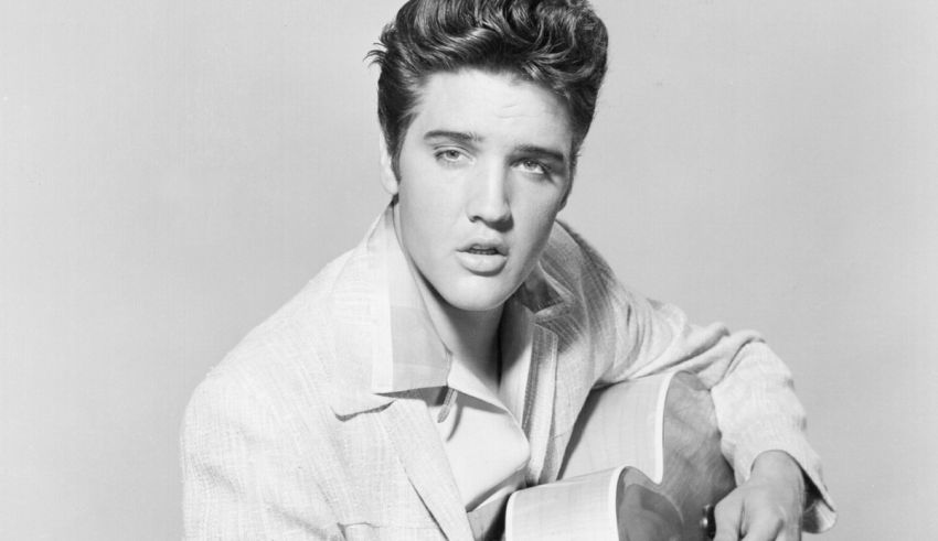 Elvis presley is holding an acoustic guitar.