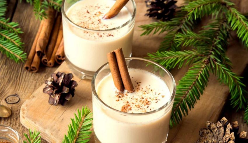Two glasses of mulled wine with cinnamon sticks on a wooden table.