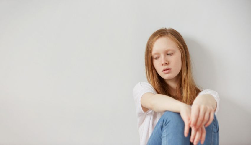 A young girl sitting on the floor with her hands on her knees.
