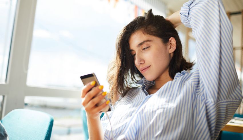 A woman looking at her phone while sitting in a chair.