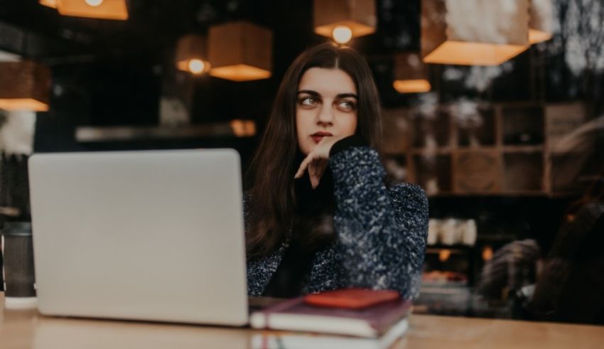 A woman sitting at a table with a laptop in front of her.