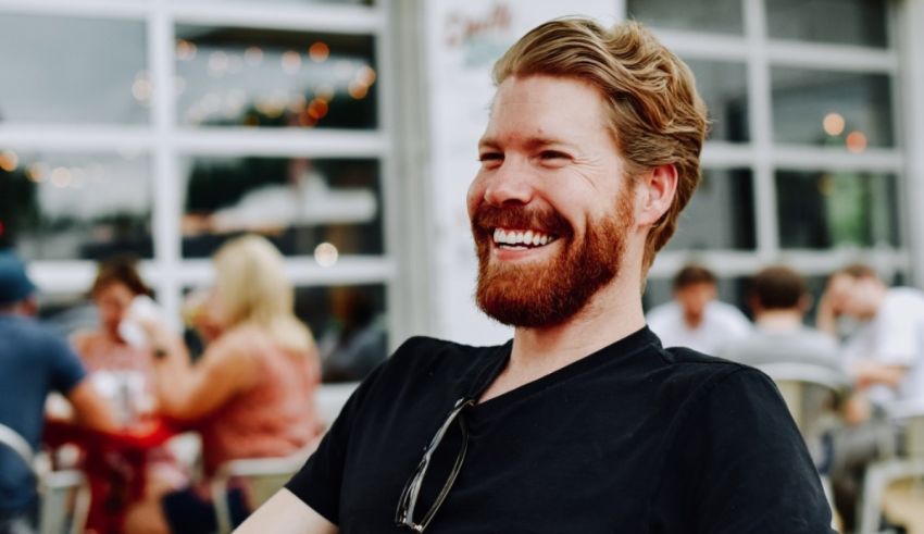A man with a beard smiling in a restaurant.