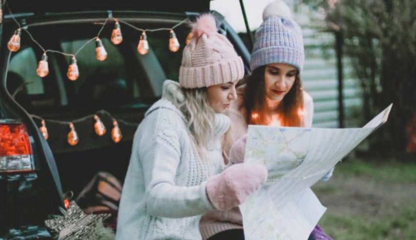 Two women looking at a map in the back of a car.