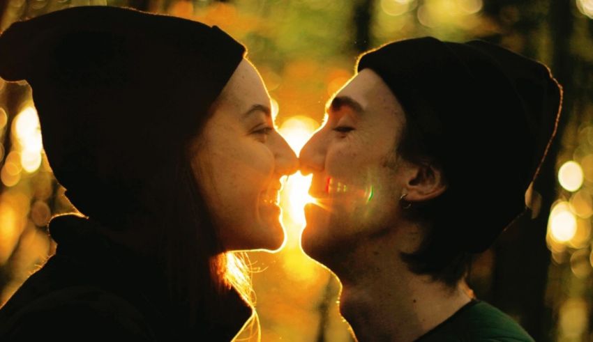A man and woman kissing in the woods.