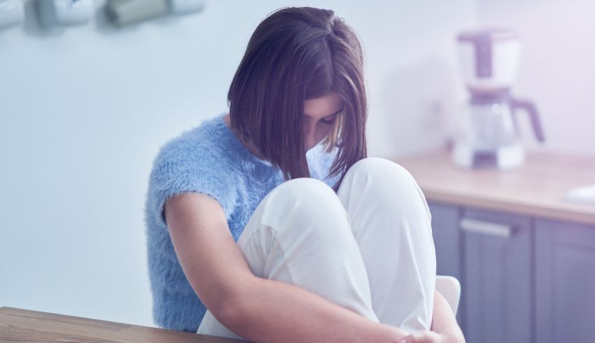A woman sitting on a kitchen counter with her hands on her knees.