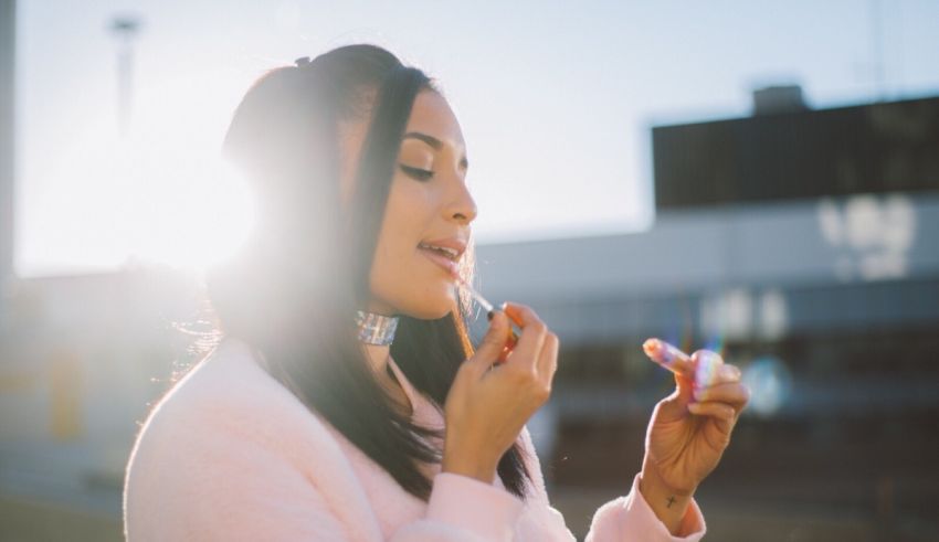 A woman is putting lipstick on her lips.