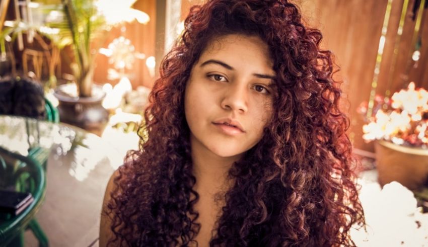 A woman with red curly hair is posing for a photo.