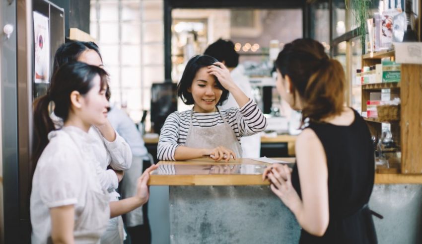 A group of women talking at a counter in a coffee shop.