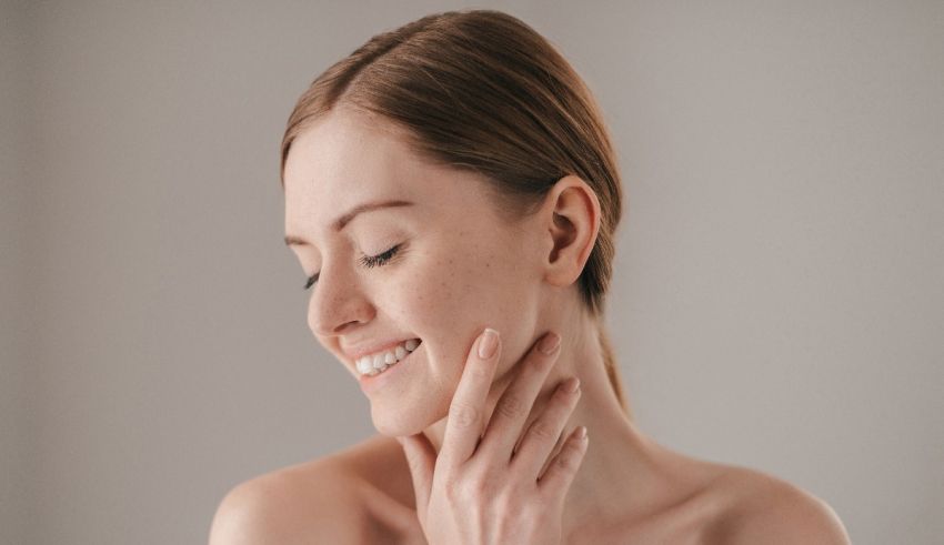 A young woman smiling with her hands on her face.