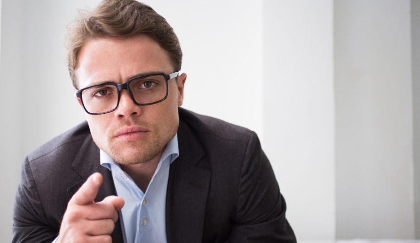 A man in glasses is pointing his finger at the camera.