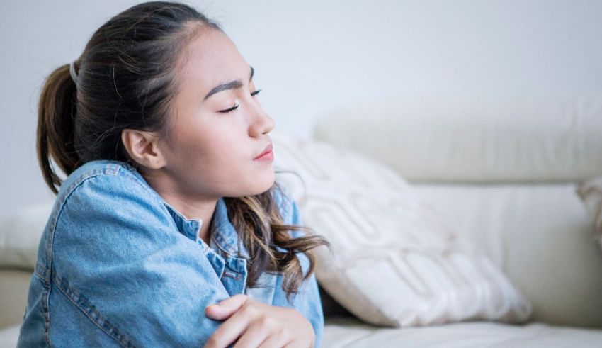 A young woman is sitting on a couch with her arms crossed.