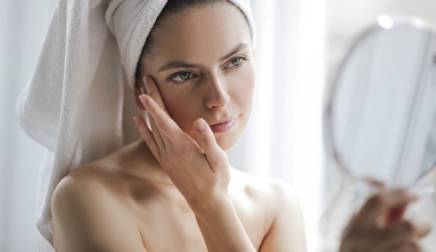 A woman looking at her face in a mirror.