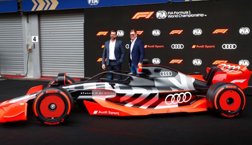 Two men standing next to an audi racing car.