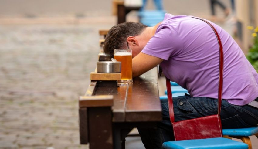 A man is sitting on a bench with a beer in his hand.