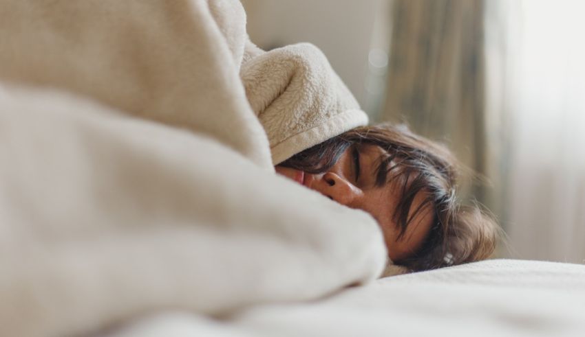 A woman is sleeping under a blanket on a bed.