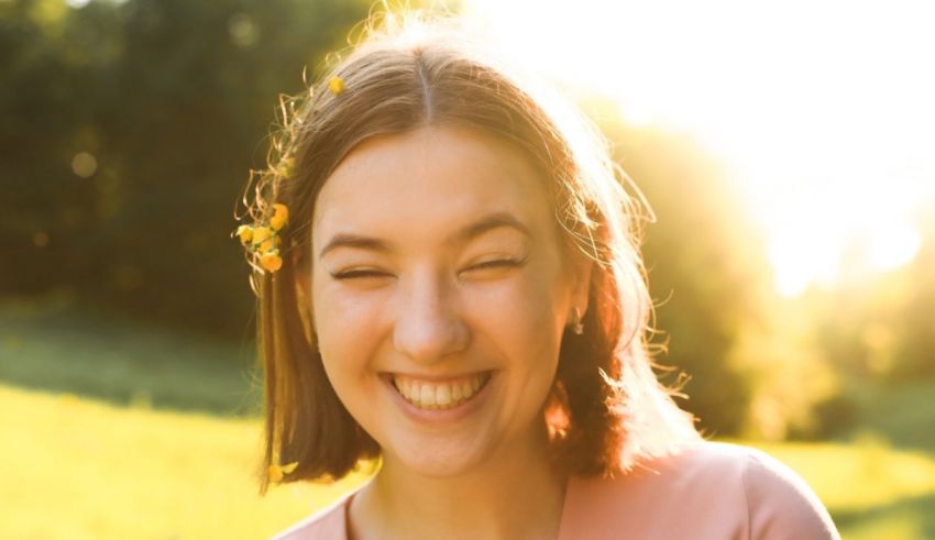 A young woman is smiling in a field at sunset.
