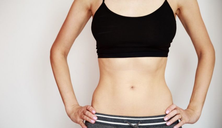A woman is posing with her hands on her stomach.