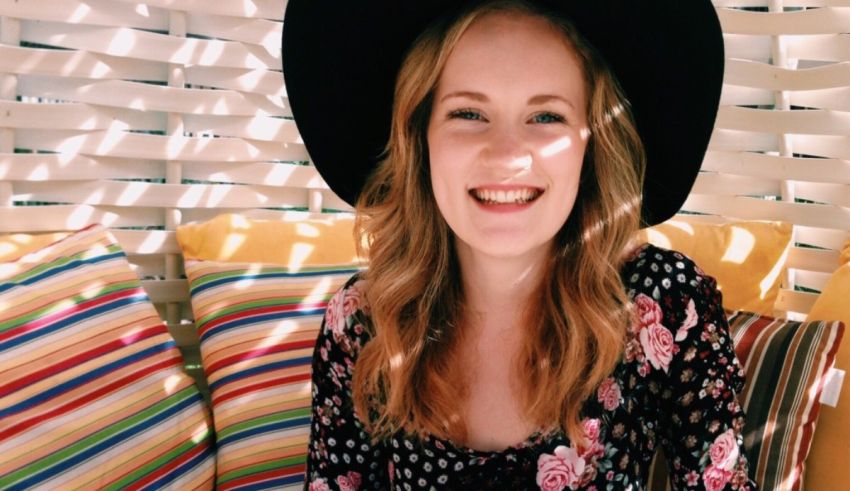 A young woman wearing a black hat sitting on a couch.