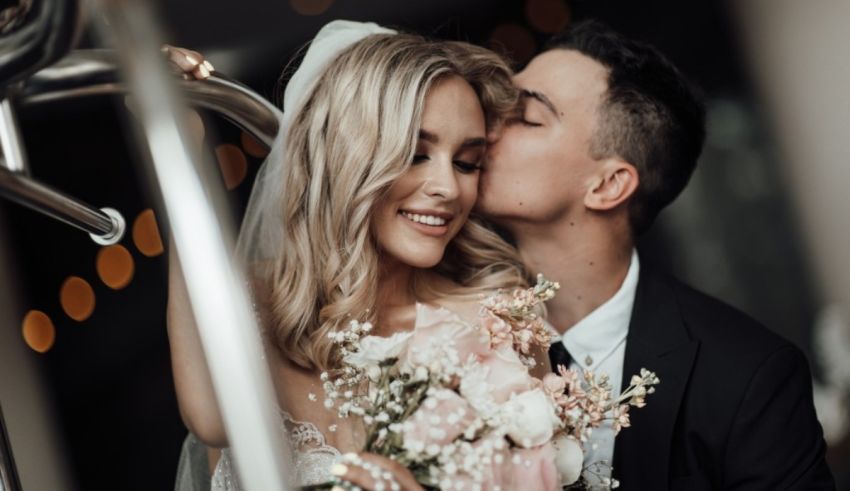 A bride and groom kissing in front of a train.