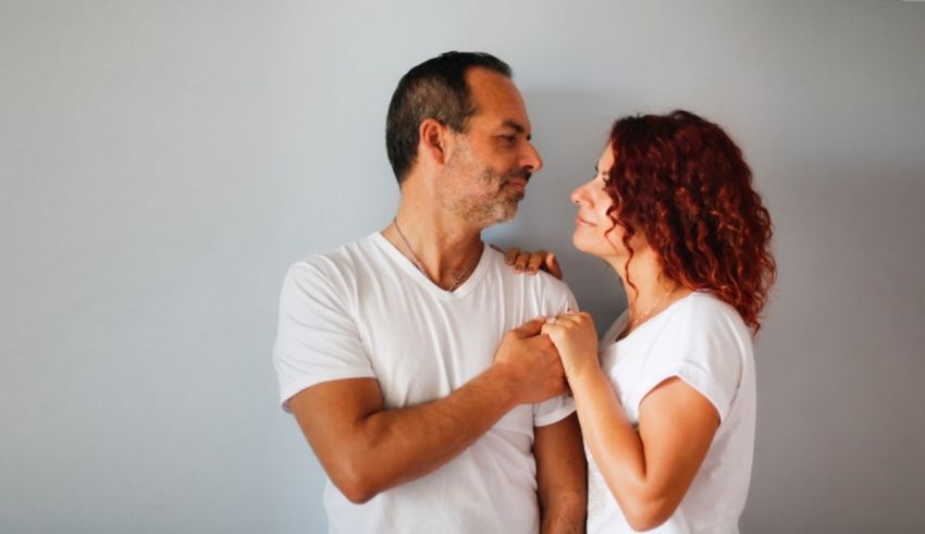 A man and woman hugging in front of a gray wall.
