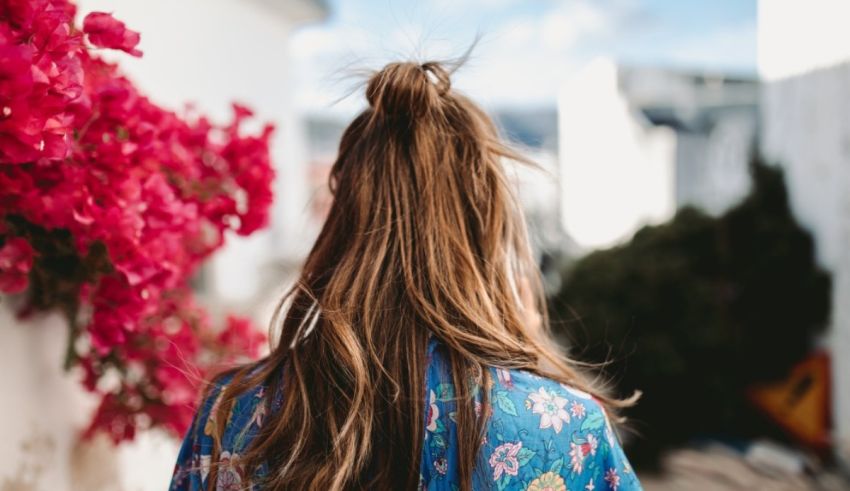 A woman in a blue kimono standing in front of flowers.